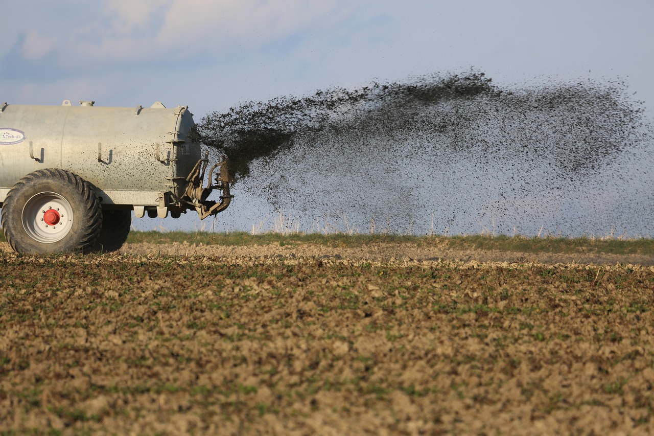 Trator espalhando fertilizantes na terra.